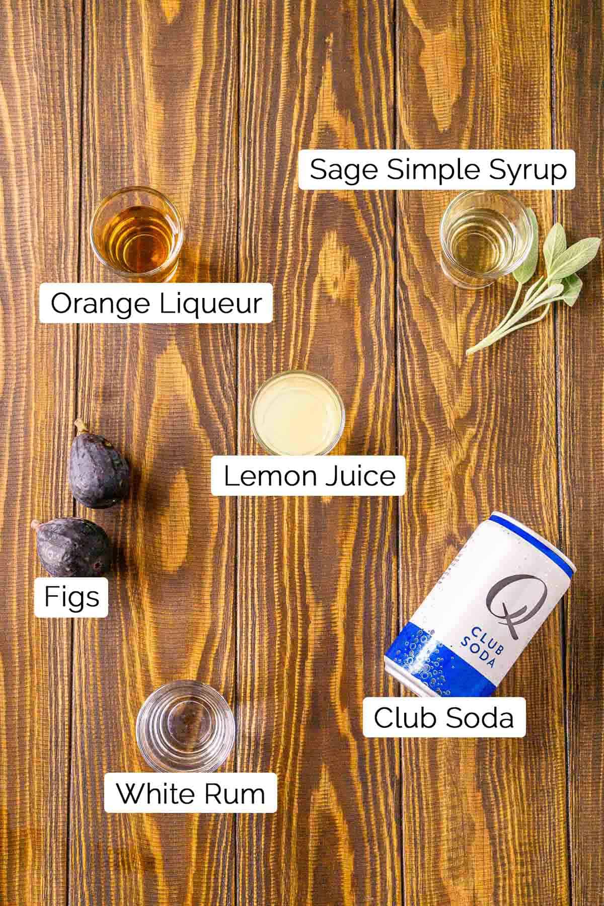 The drink ingredients in shot glasses on a wooden surface with black and white labels.