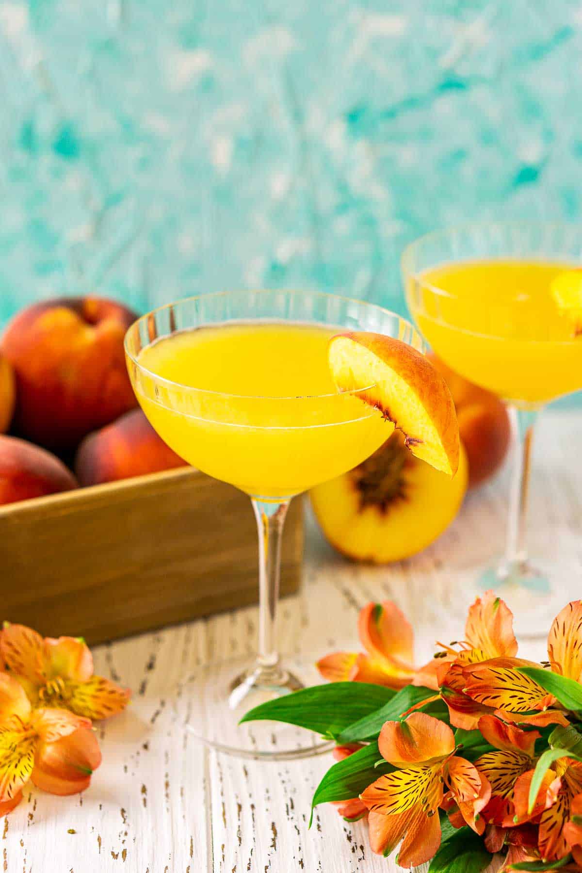 Looking down on a peach daiquiri with a bundle of orange flowers to the side and a few single flower buds to the left.