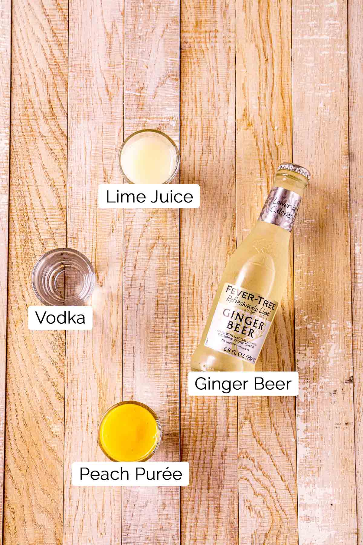 The cocktail ingredients on a cream-colored wooden board with black and white labels.