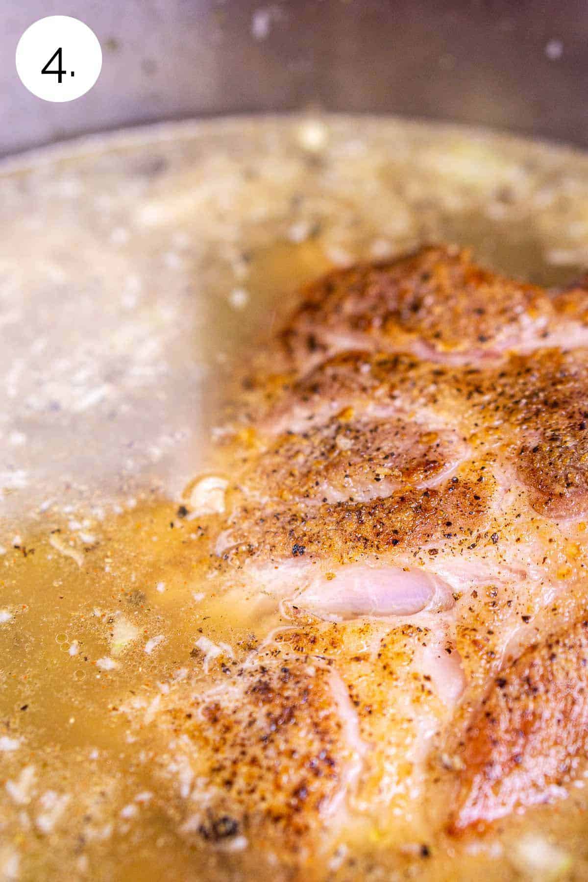 The pork shoulder back in the stockpot with the broth, chiles and spices as it comes to a boil.