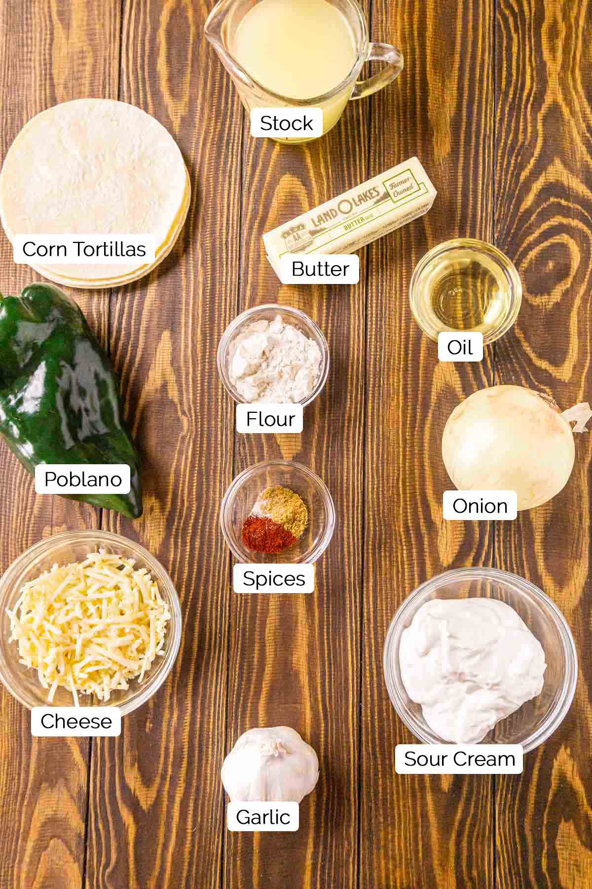 The enchilada ingredients on a wooden board with white and black labels with each food item.