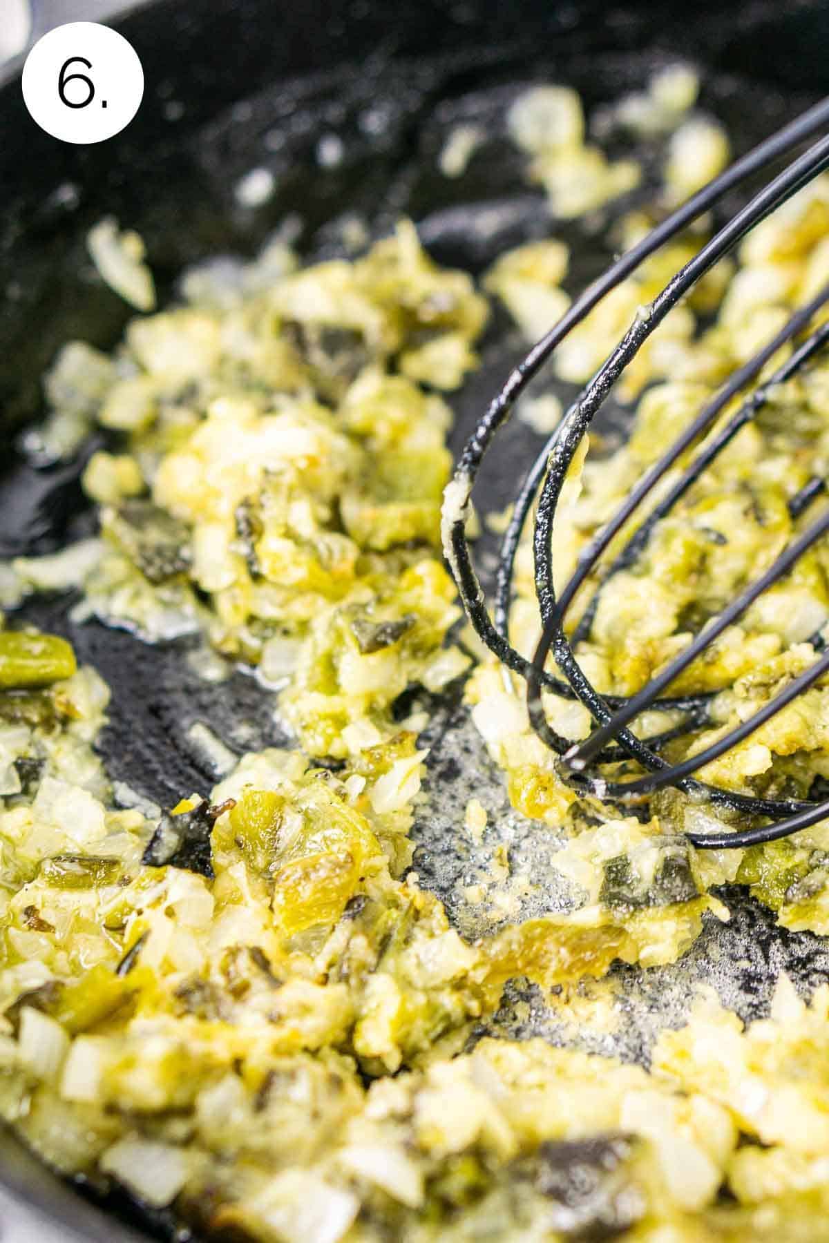 Whisking flour into the butter, peppers, onion and garlic in a cast-iron skillet to make the roux.