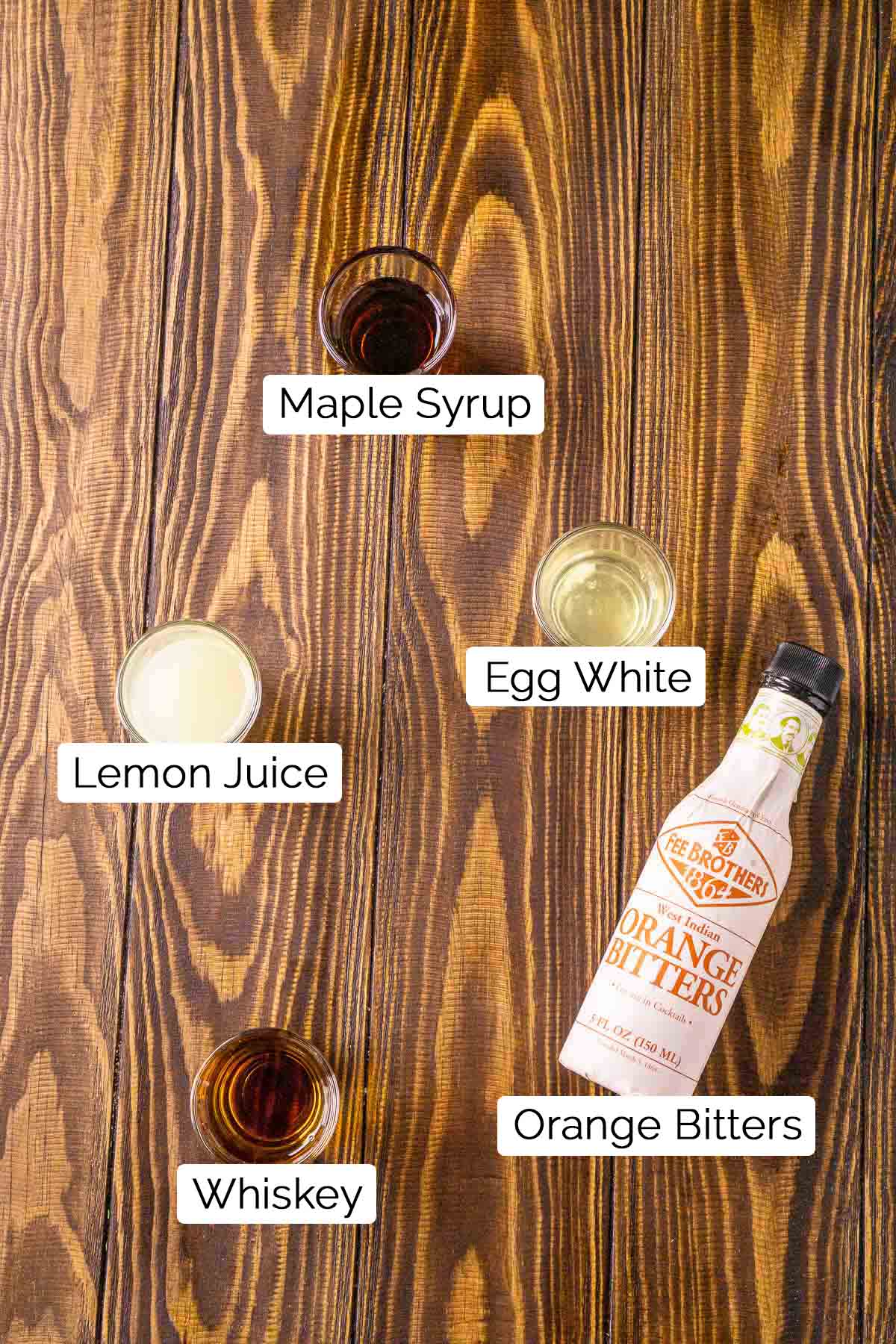 The drink ingredients on a brown wooden board with black and white labels.