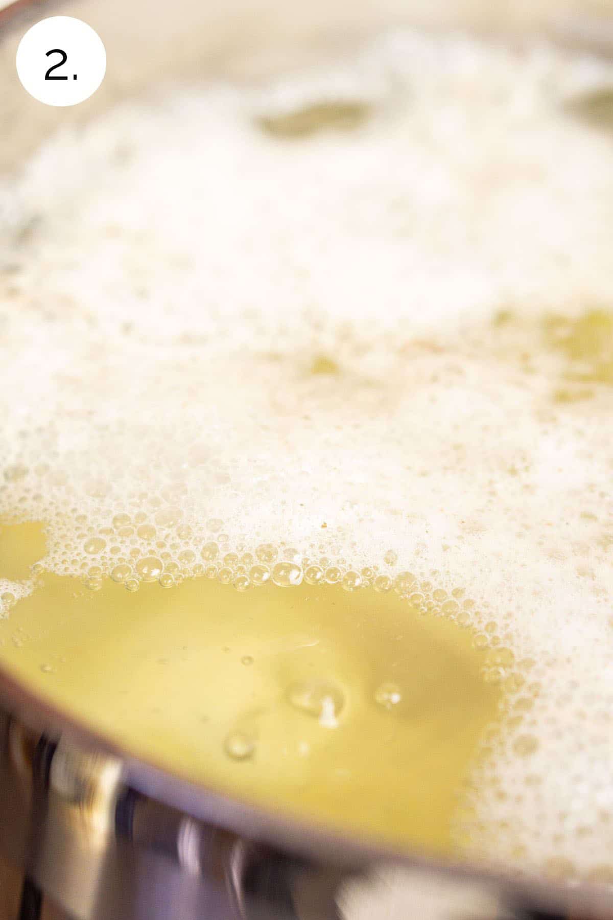 The potatoes simmering in water in a large stainless steel stock pot on the stove-top.