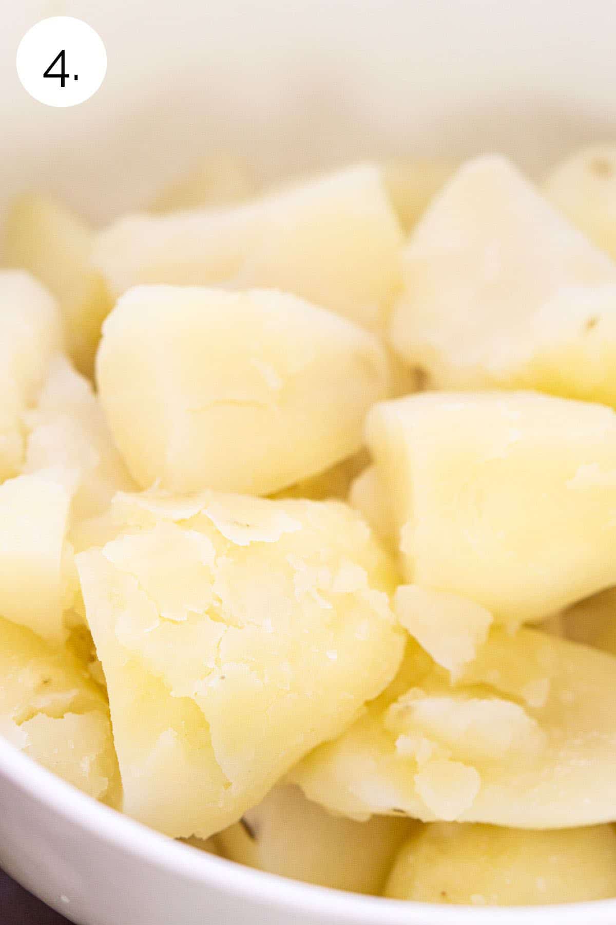 The potatoes in a white strainer in the kitchen sink after simmering until tender.