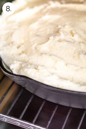 The cast-iron skillet filled with the mashed potatoes on the grates of the smoker.