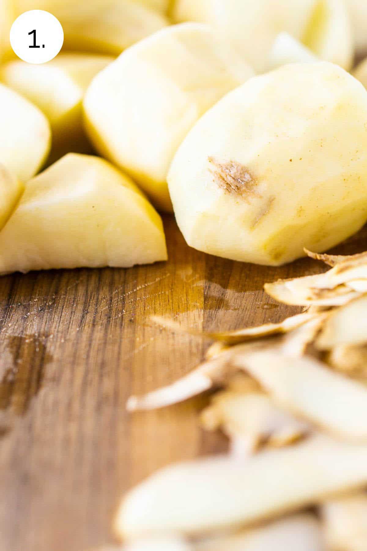 The russet potatoes peeled on a wooden cutting board before boiling and simmering.