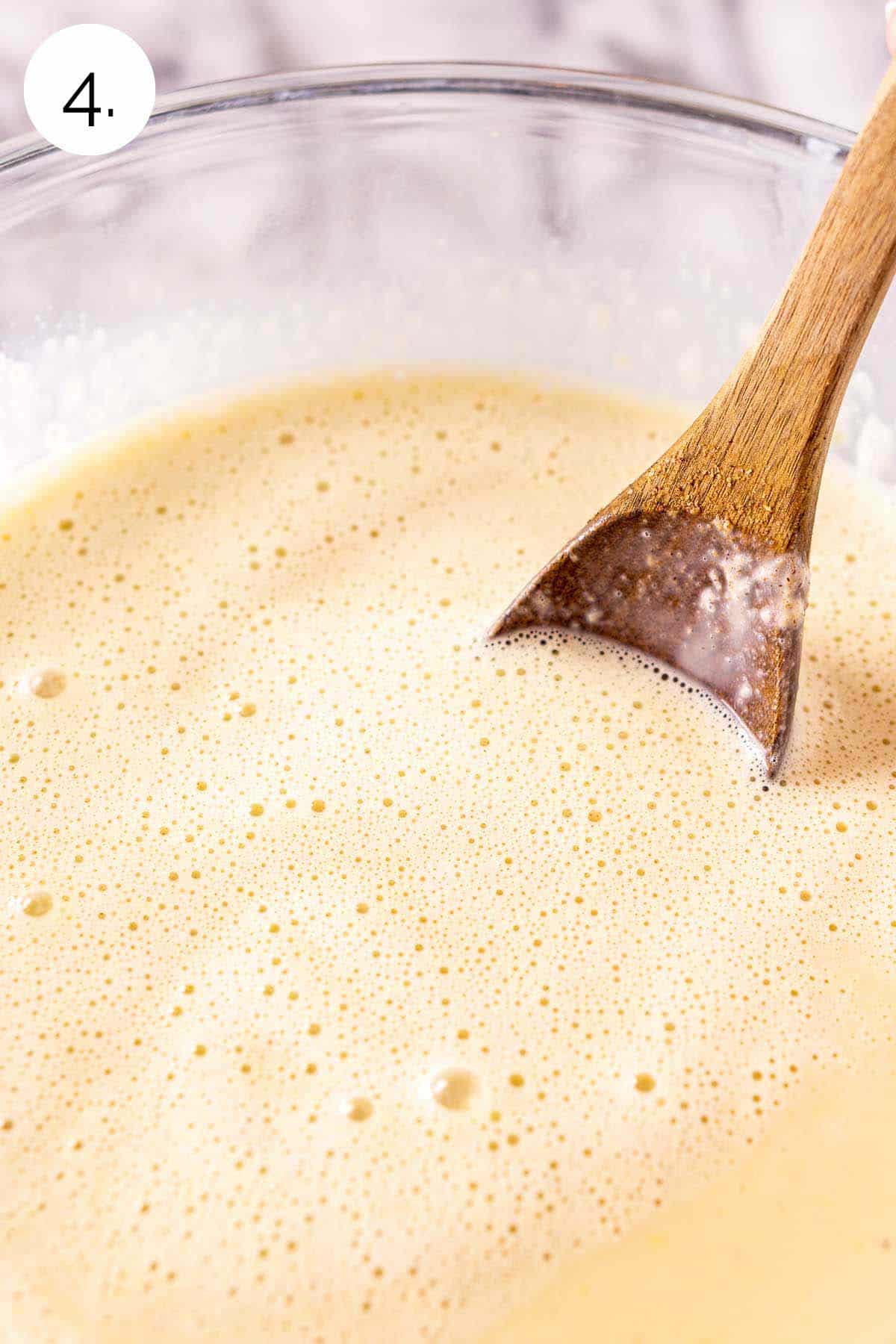 Stirring the Baileys into the egg mixture with a wooden spoon in a large glass mixing bowl.