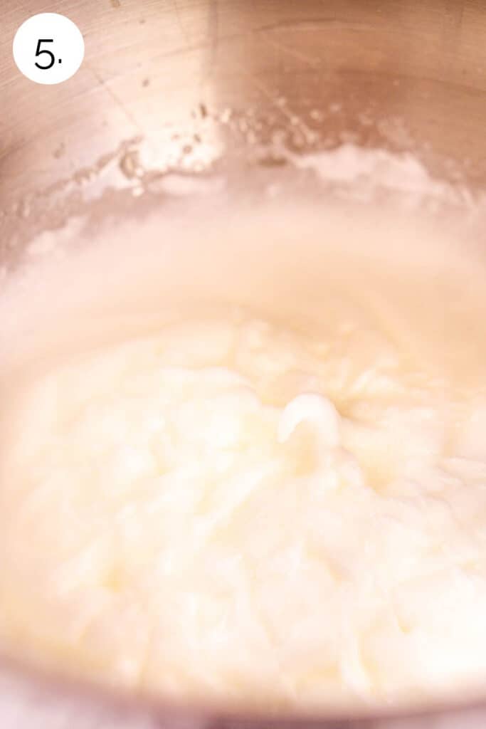The egg whites whipped into forming soft peaks in a large stainless steel mixing bowl.