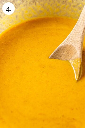 A wooden spoon stirring the pumpkin mixture in a large glass bowl until it's nice and smooth.