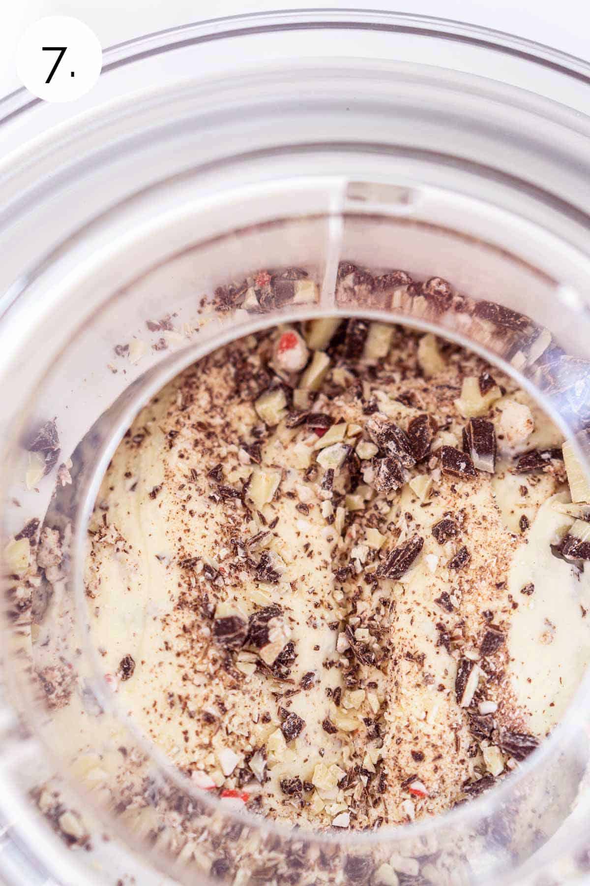The chopped peppermint bark in an ice cream maker at the end of the churning process to combine.