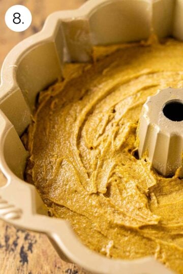 The cake batter poured into the gold bundt pan on a wooden surface before baking in the oven.