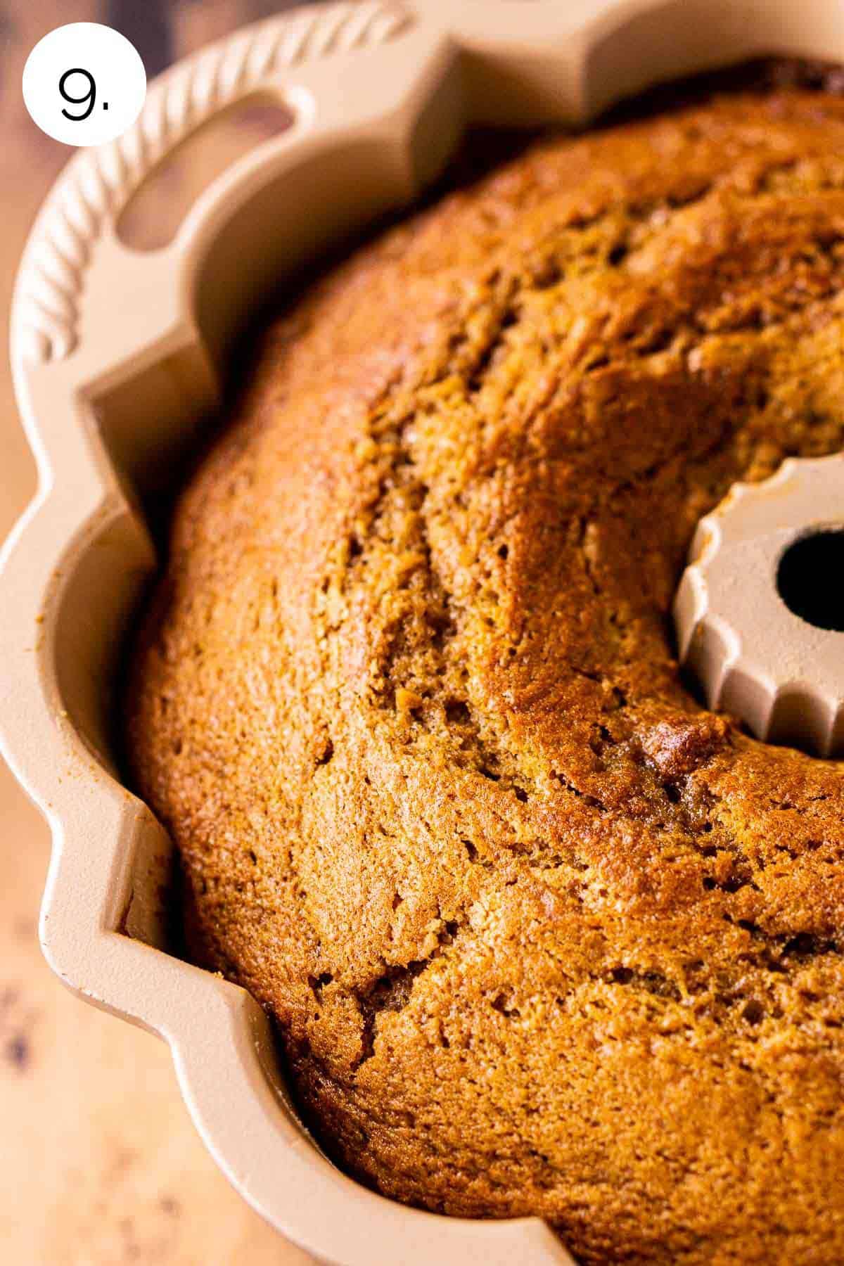 The cake in the gold bundt pan on a wooden surface after it finished baking in the oven.