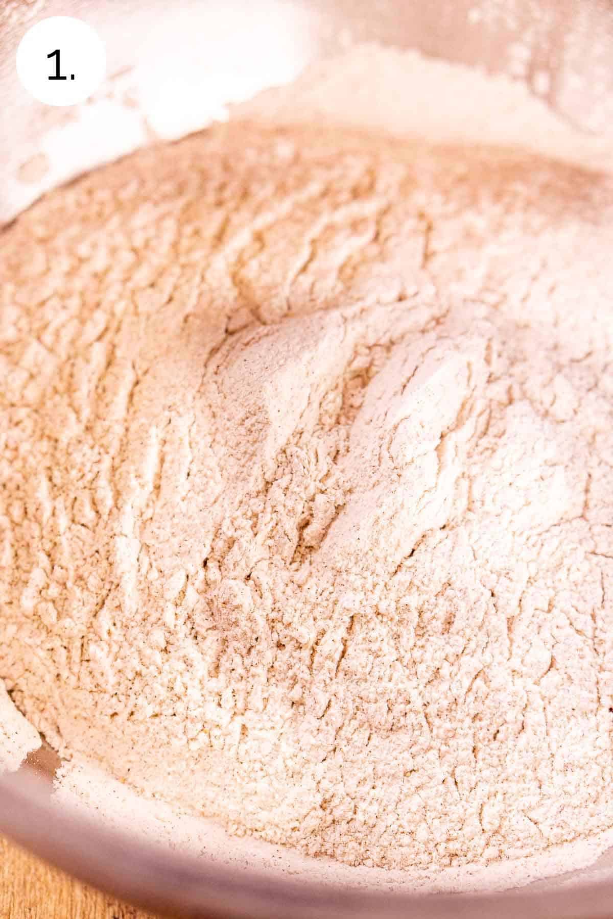 The dry ingredients mixed together in a large stainless steel bowl on a wooden surface.