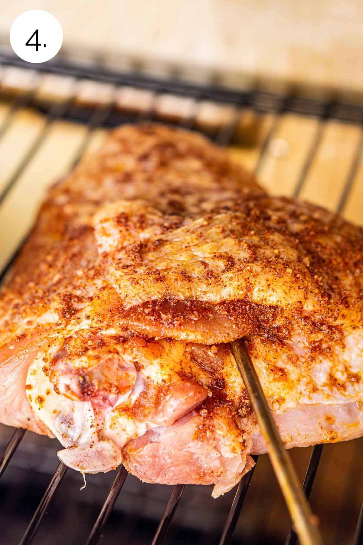 The turkey on the grill grates with a leave-in meat thermometer inserted into the meat.