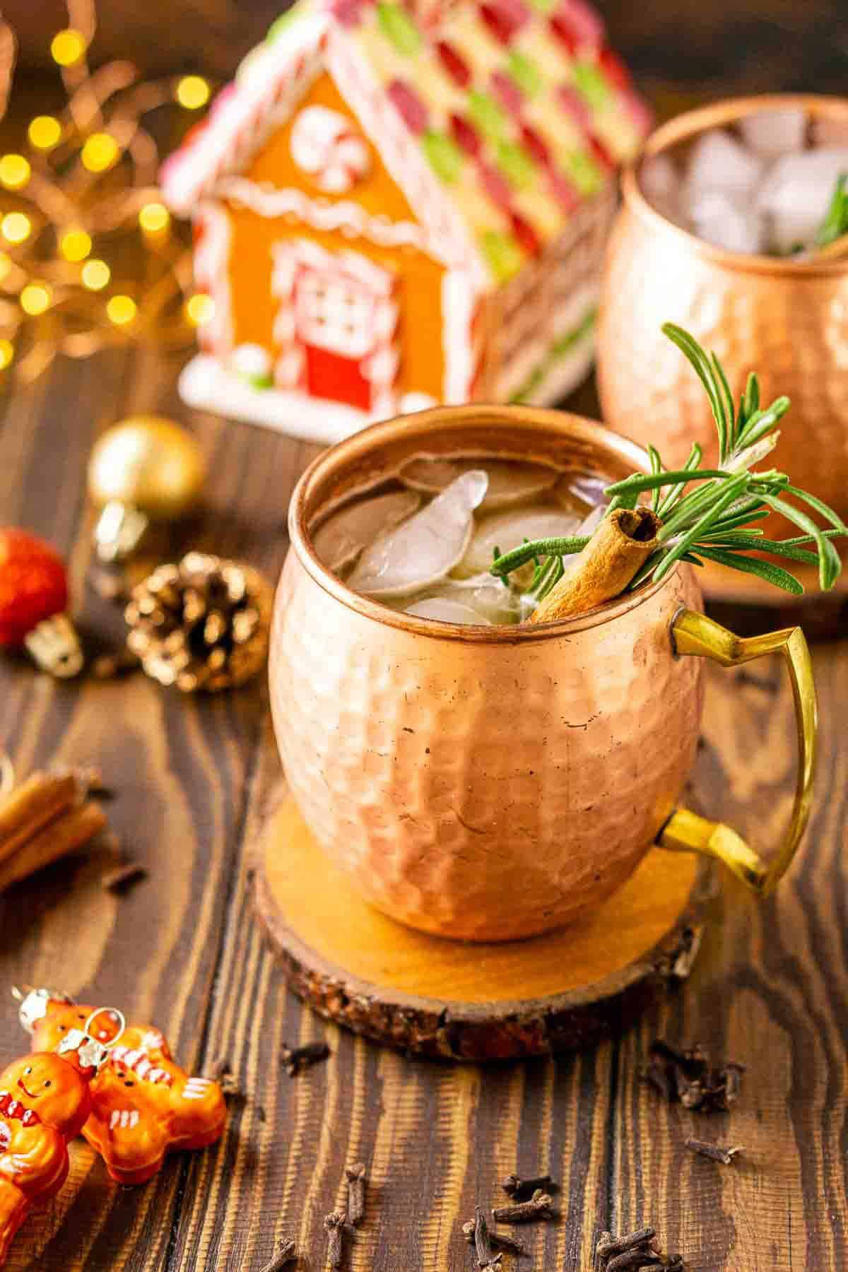 A gingerbread mule on a wooden coaster with Christmas decor and spices around it on a brown surface.