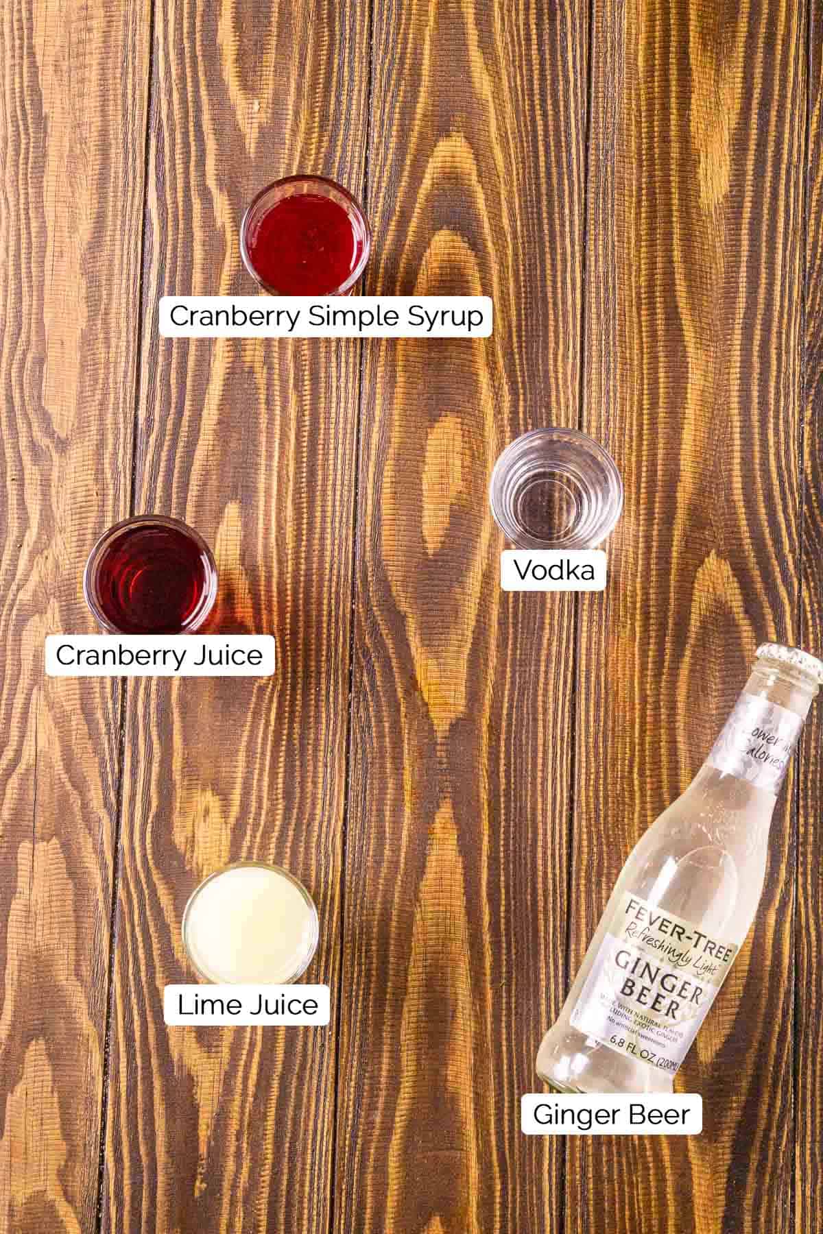 The mule ingredients on a brown wooden surface with black and white labels underneath all five items.