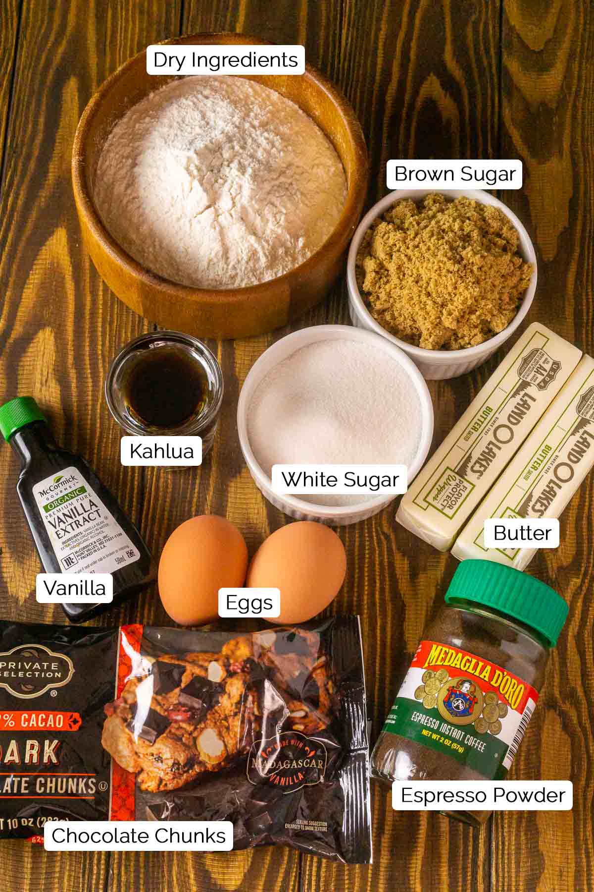 The cookie ingredients on a brown wooden board with black and white labels by each item.