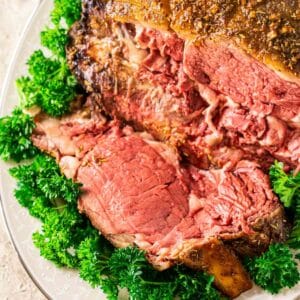 An aerial view of the smoked prime rib roast with a couple pieces carved off on a cream-colored platter.