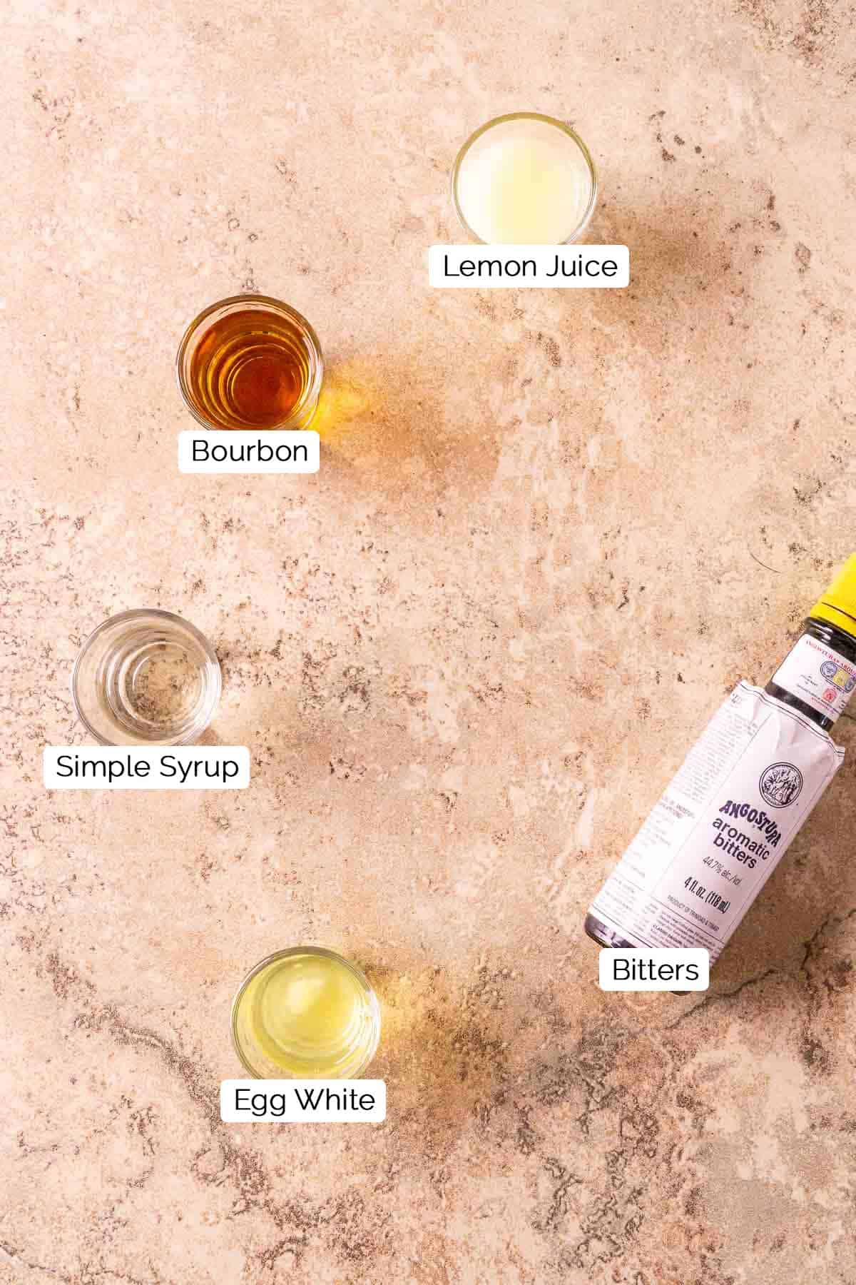 The drink ingredients on a cream-colored marble surface with black and white labels.