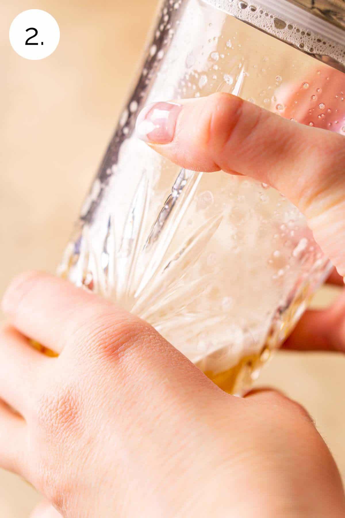 Two hands shaking the drink in a crystal cocktail shaker without ice to take care of the dry shake process.