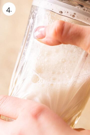 Two hands holding a crystal cocktail shaker to conduct the wet shake process.