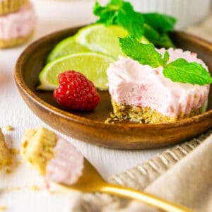A mini raspberry mojito pie with a scoop taken out of it on a wooden plate with a gold spoon holding some of the pie in front.