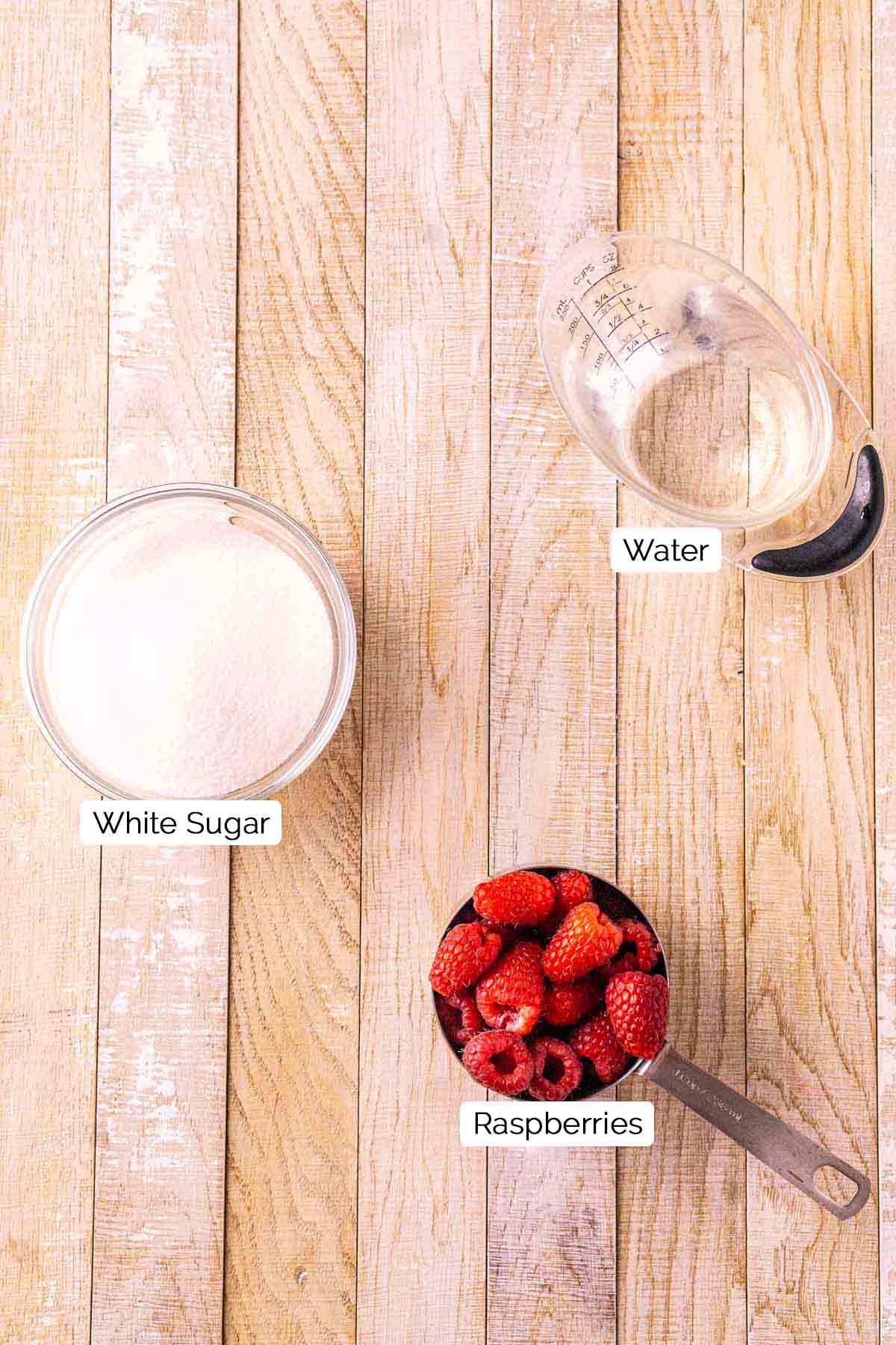 The syrup ingredients on a cream-colored wooden board with black and white labels by the three items.