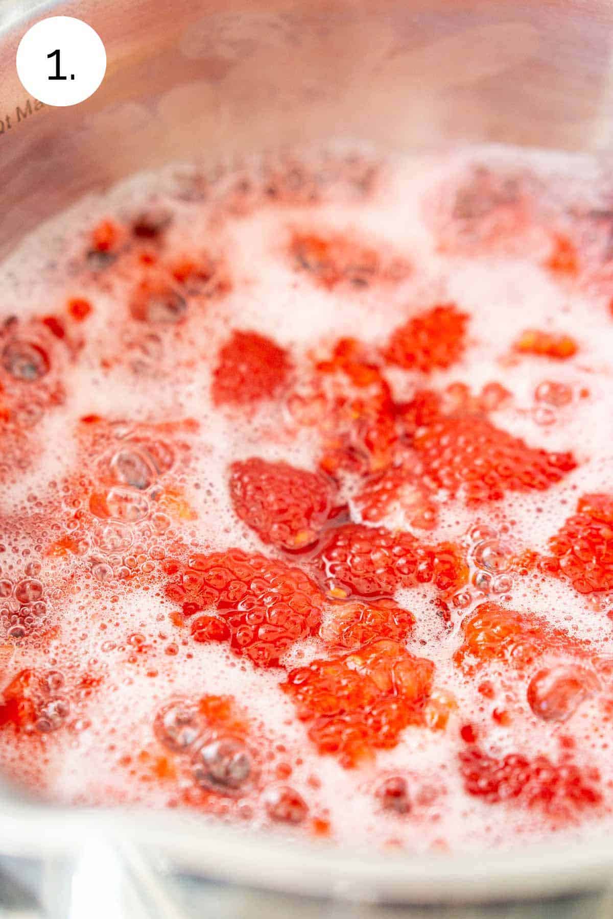 The raspberry mixture boiling in a small stainless steel saucepan on a stove-top range.