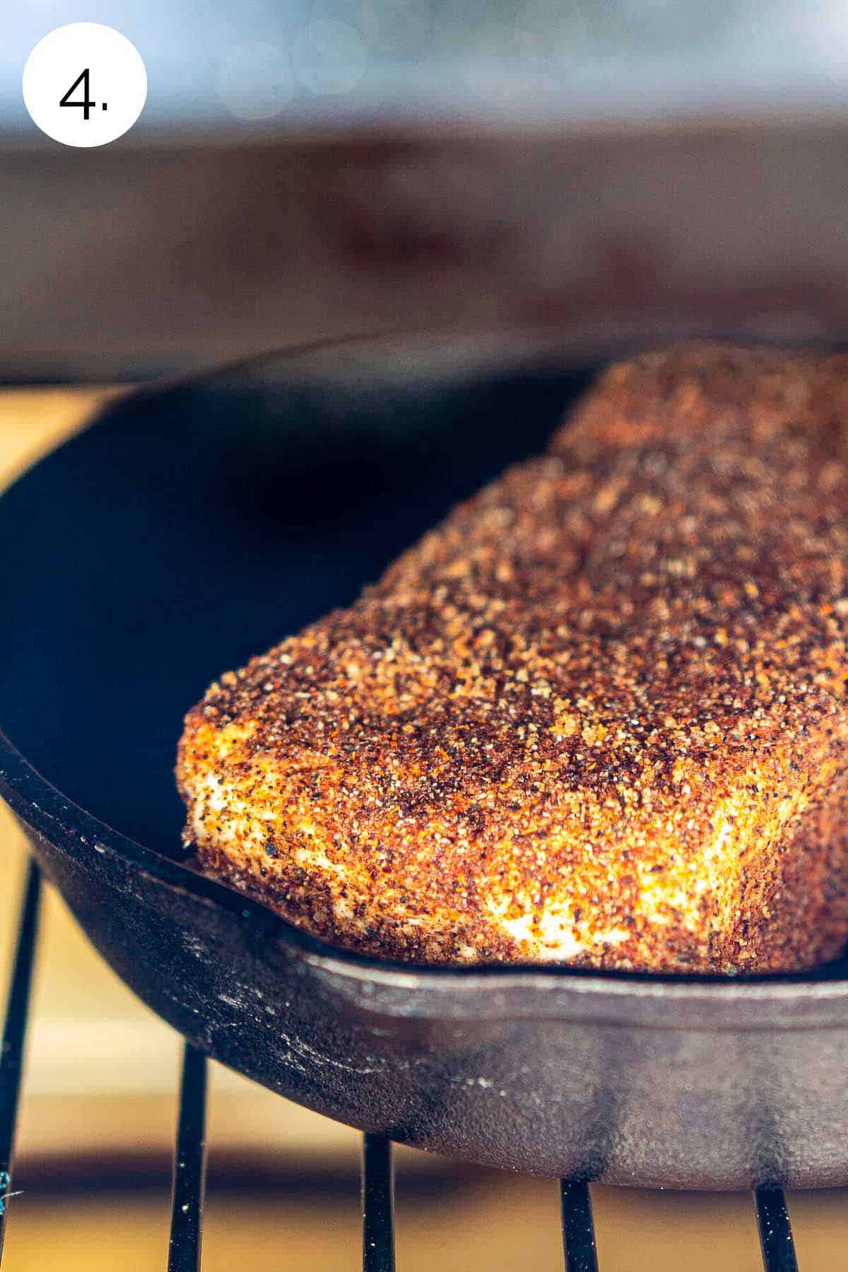 The seasoned cream cheese in a miniature cast-iron skillet on the grill grates before closing the lid to smoke.