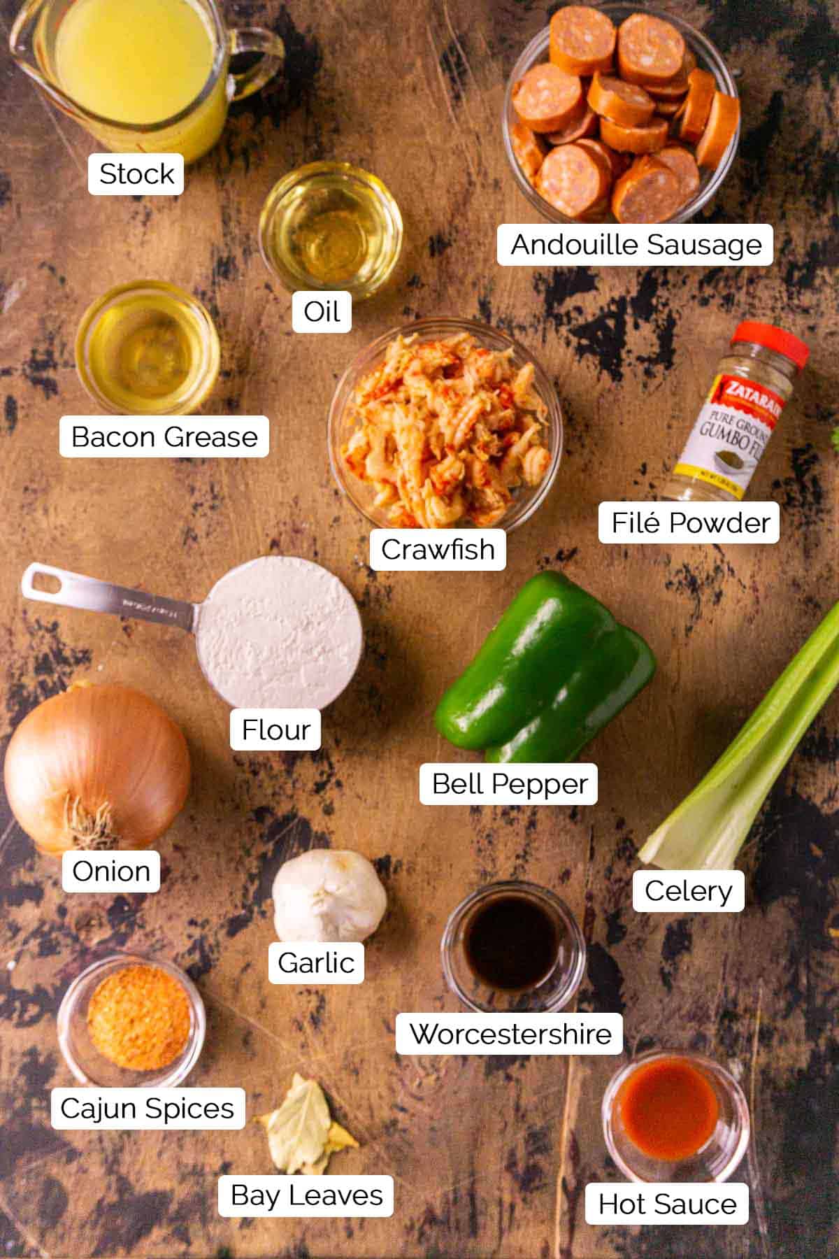 The gumbo ingredients on a rustic wooden board with black and white labels by each item.