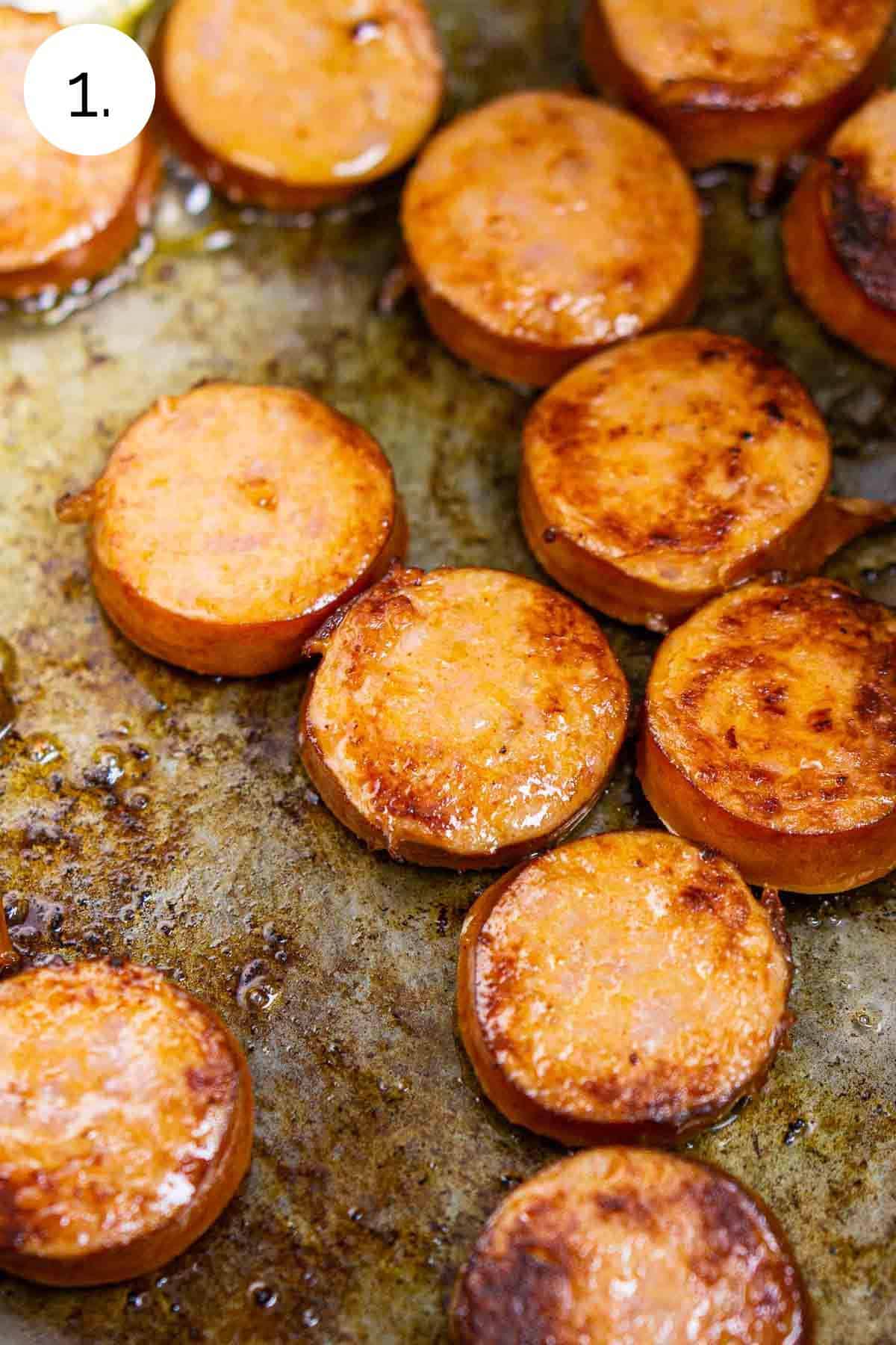 Slices of andouille sausage in a large stainless steel stock pot after browning on one side.