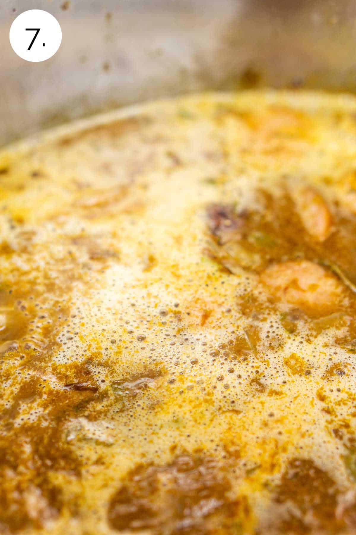 Bringing the gumbo to a simmer in a large stainless steel stock pot before covering.