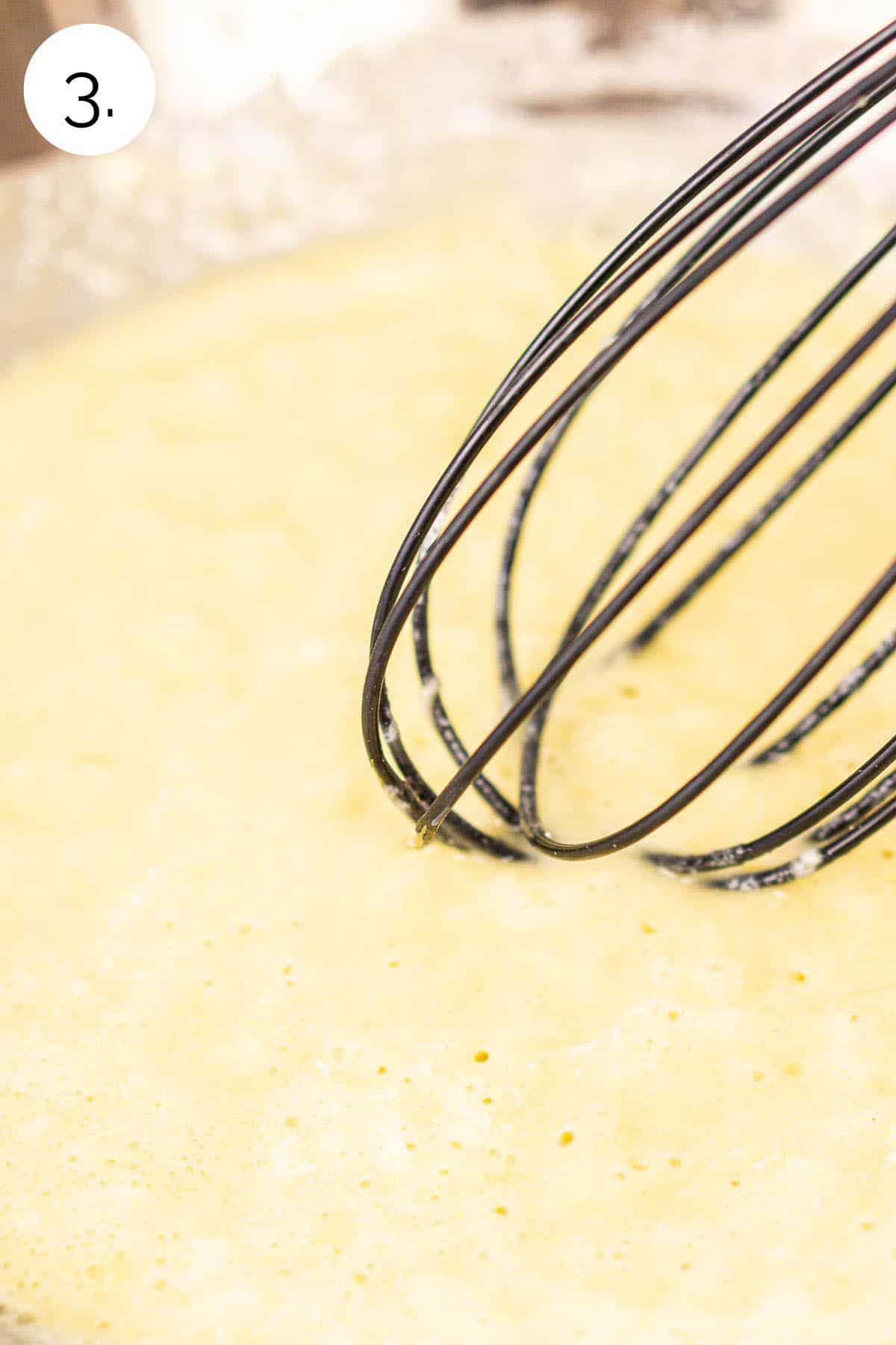 Whisking the flour into the butter and garlic mixture on the stove until it becomes one cohesive mixture.