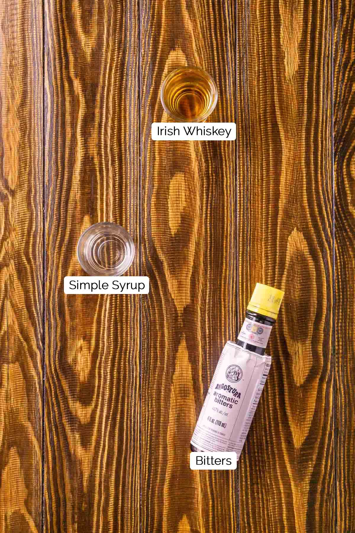 The drink ingredients on a brown wooden board with white and black labels underneath the three items.
