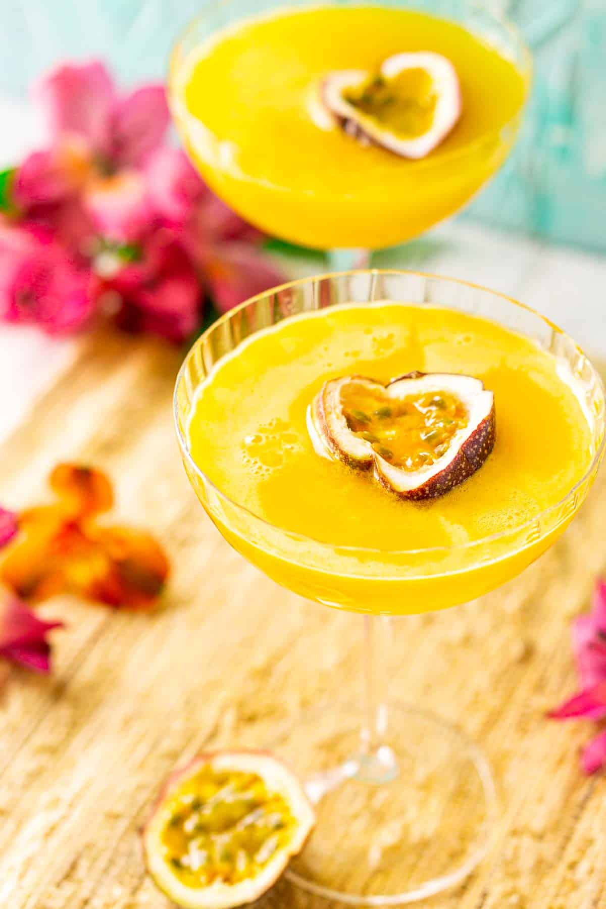A close-up view of the passion fruit martini on a straw placemat with half of a fresh passion fruit to the side of the glass.