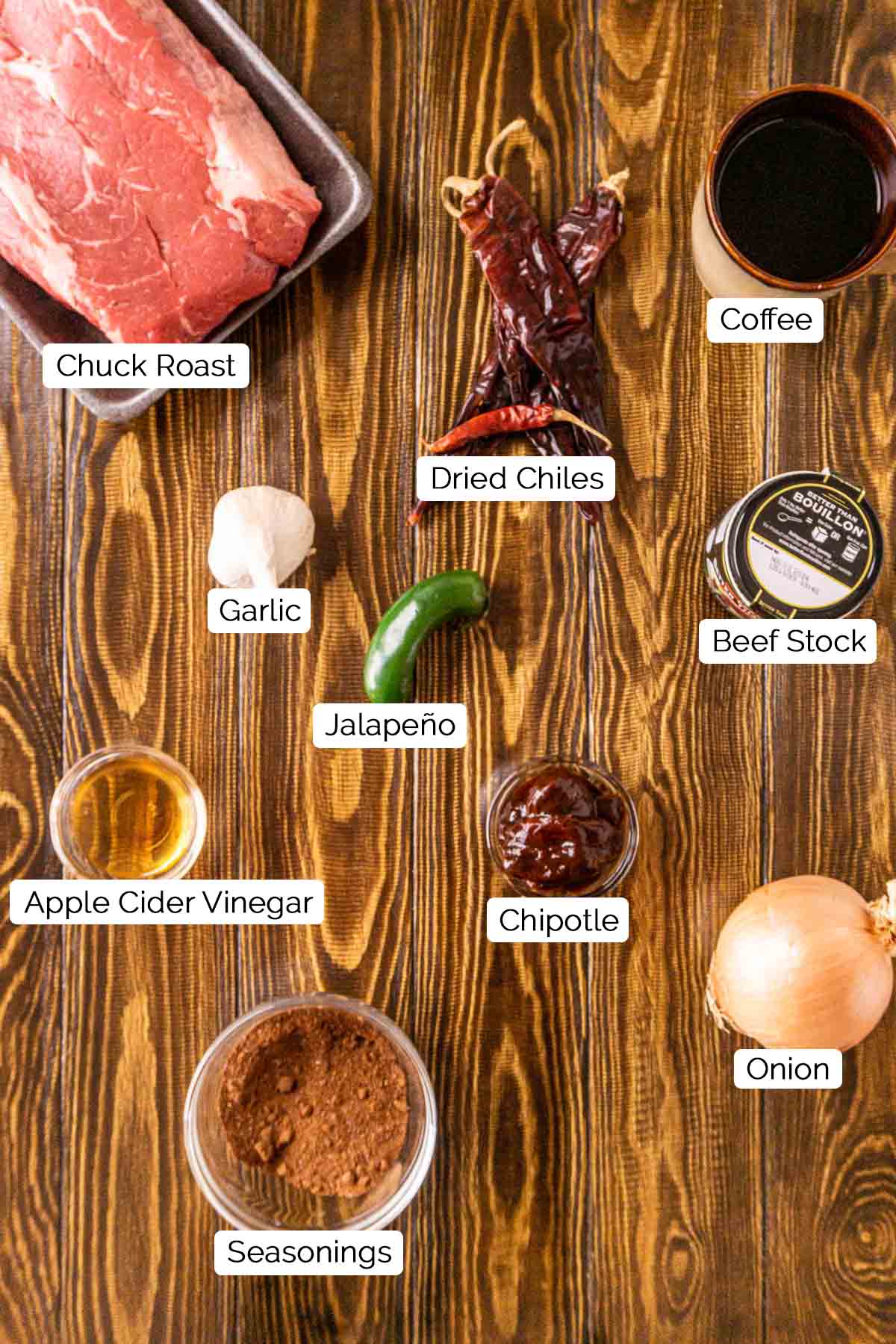 The chili ingredients on a brown wooden board with white and black labels underneath all the items.