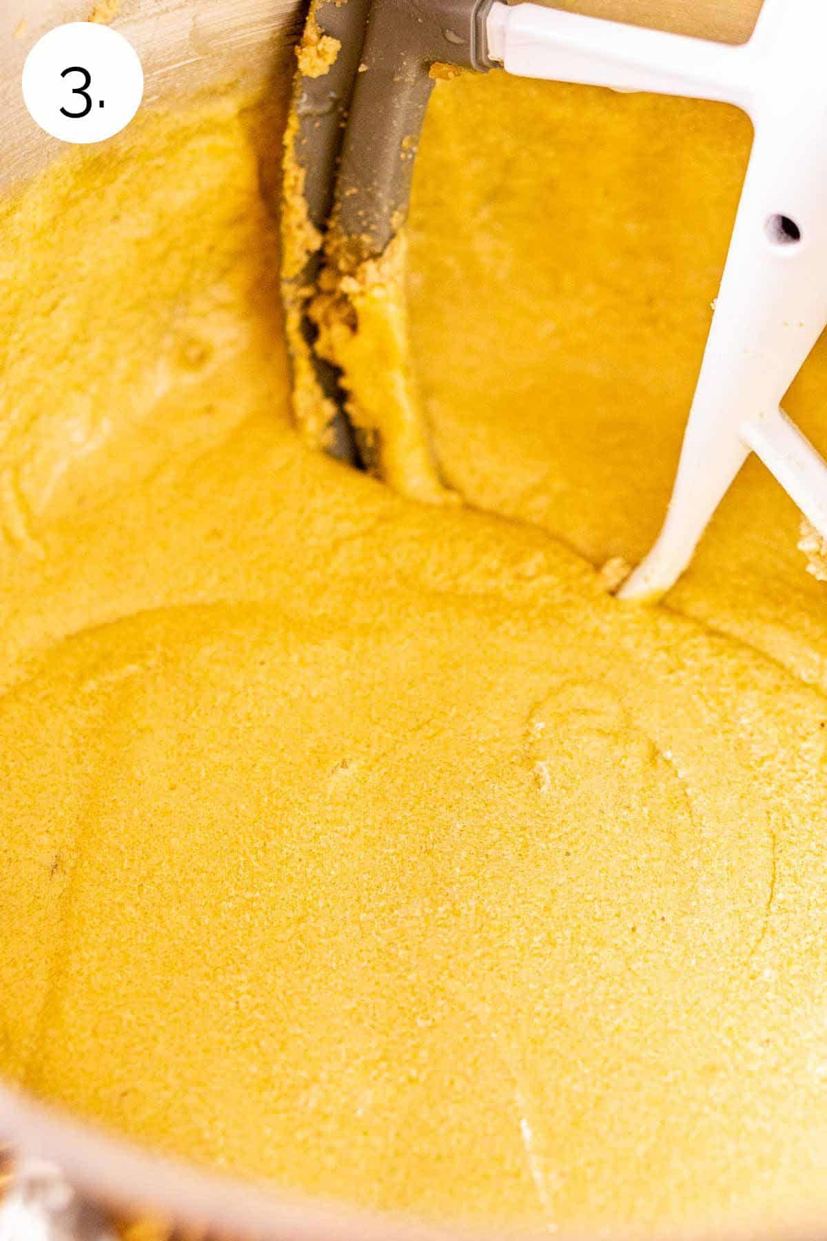 The batter after the eggs have been added to the butter mixture in a stainless steel mixing bowl.