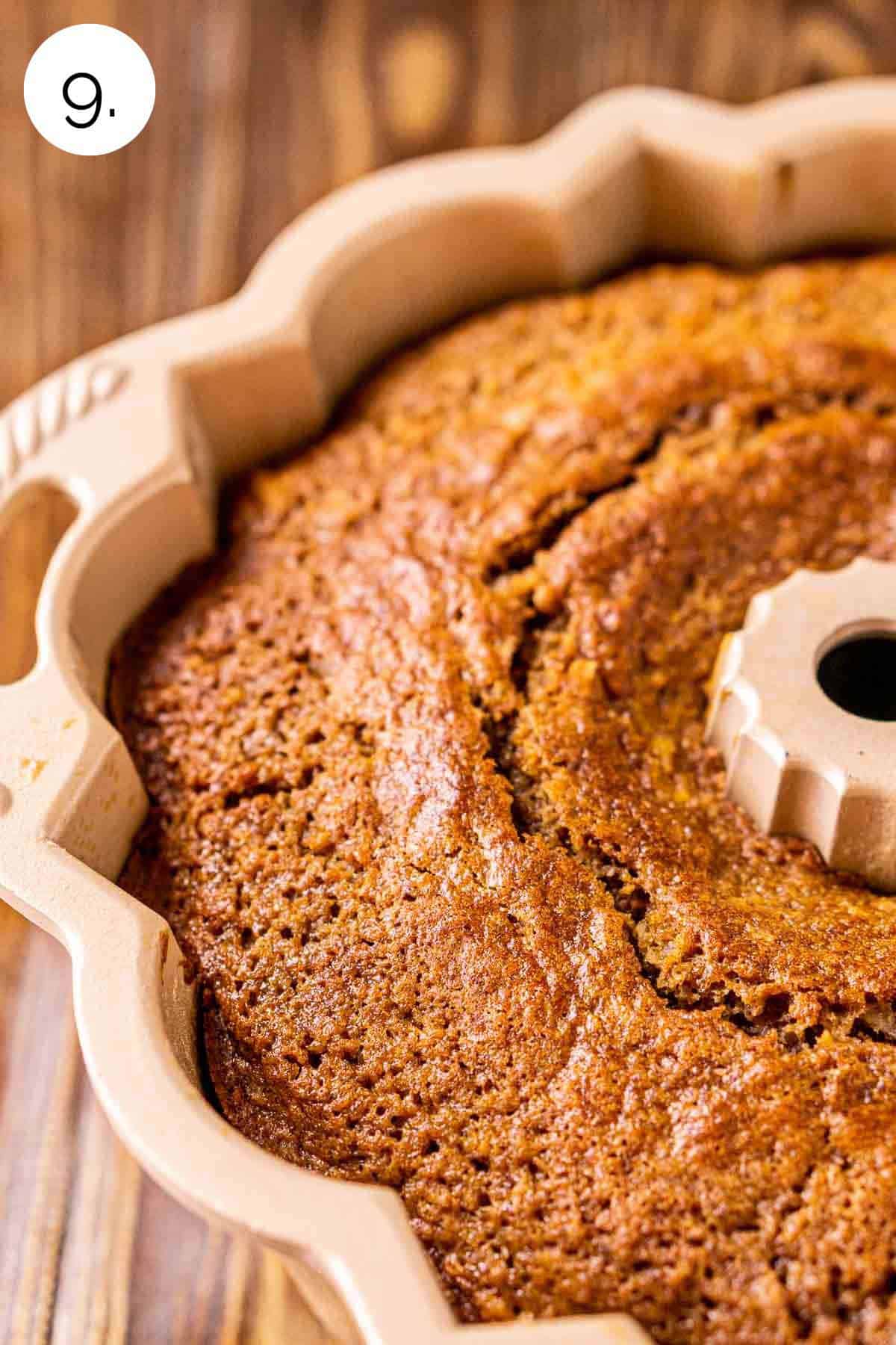 The carrot pound cake in the gold bundt pan on a wooden surface right after it came out of the oven.