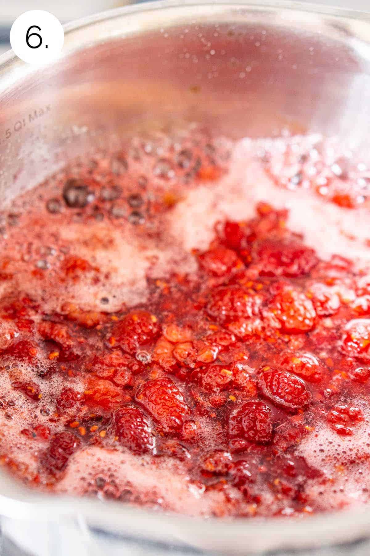 Boiling the water, sugar and raspberries in a small stainless steel saucepan on the stove to make the syrup.