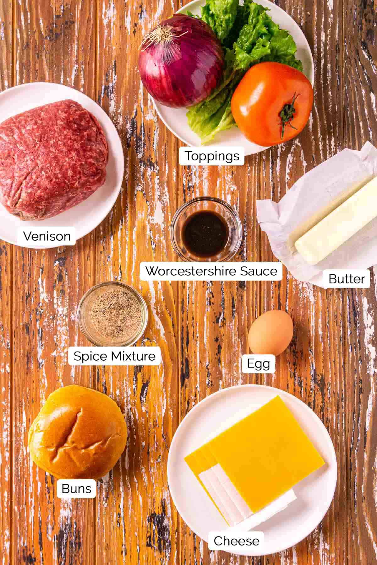 The burger ingredients on a wooden and white surface with black and white labels underneath the various items.