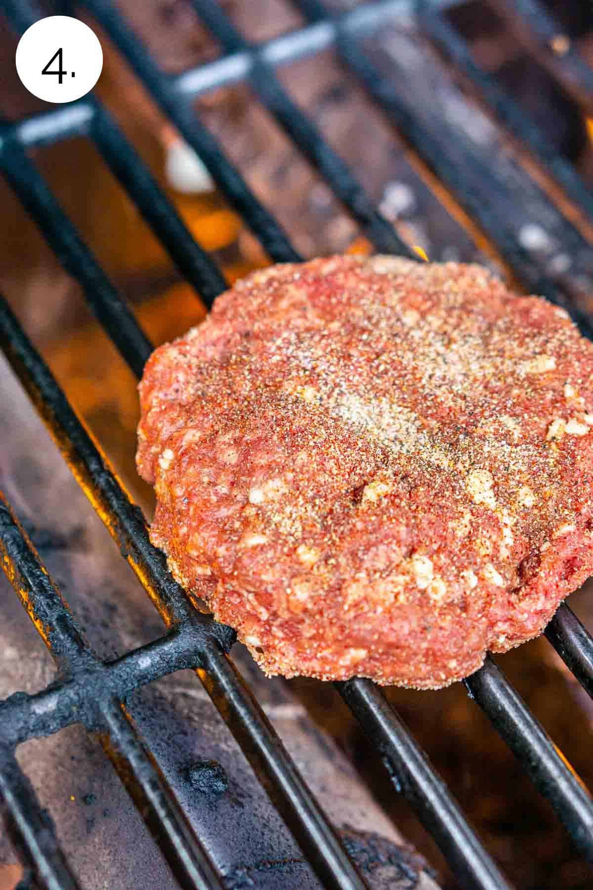Two burger patties on a grill before closing the lid to cook on one side.