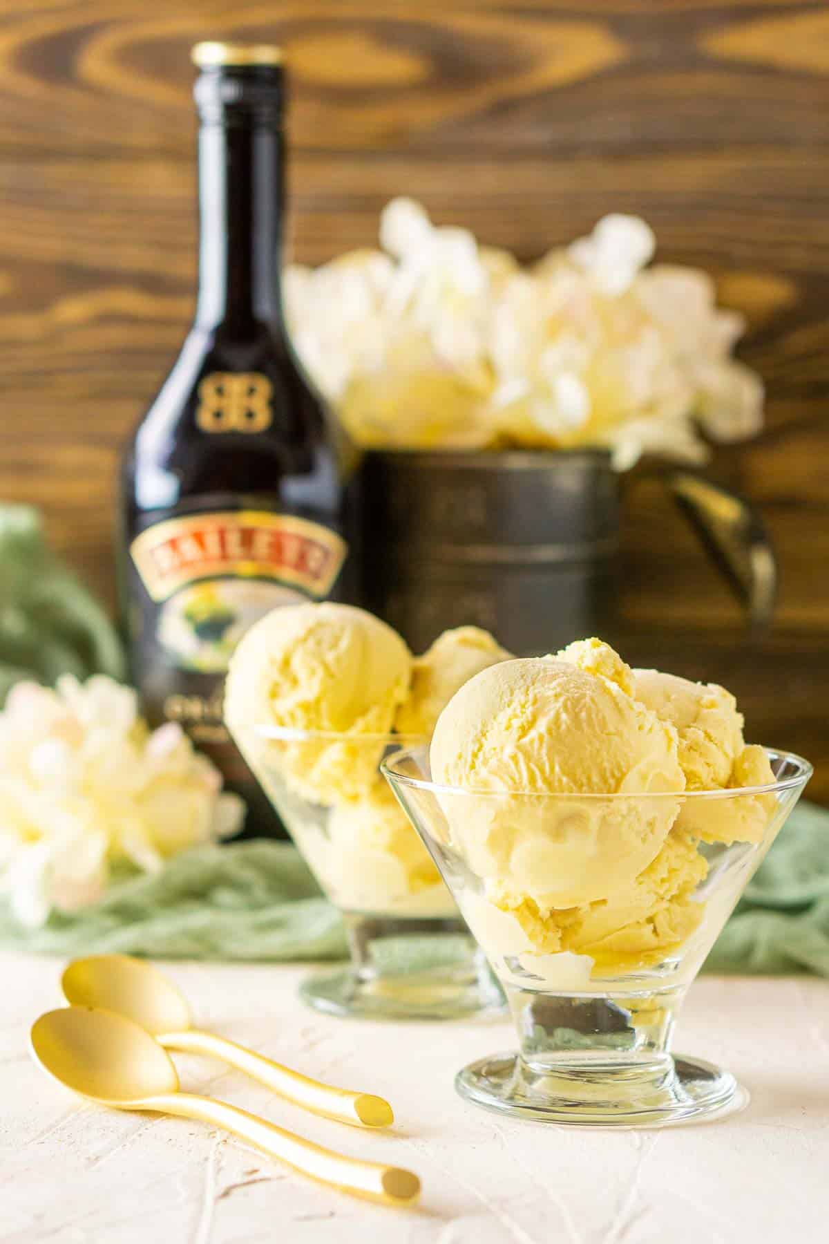 Two glass cups of Baileys ice cream with gold spoons on the side.
