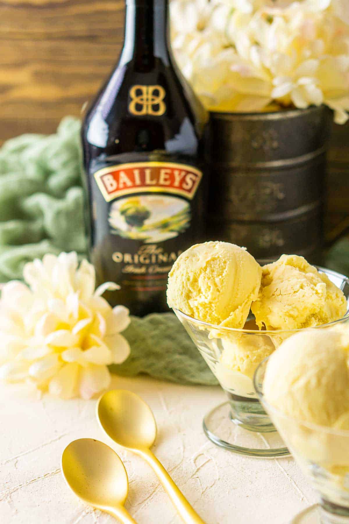 A glass cup with Baileys ice cream and flowers in the background.