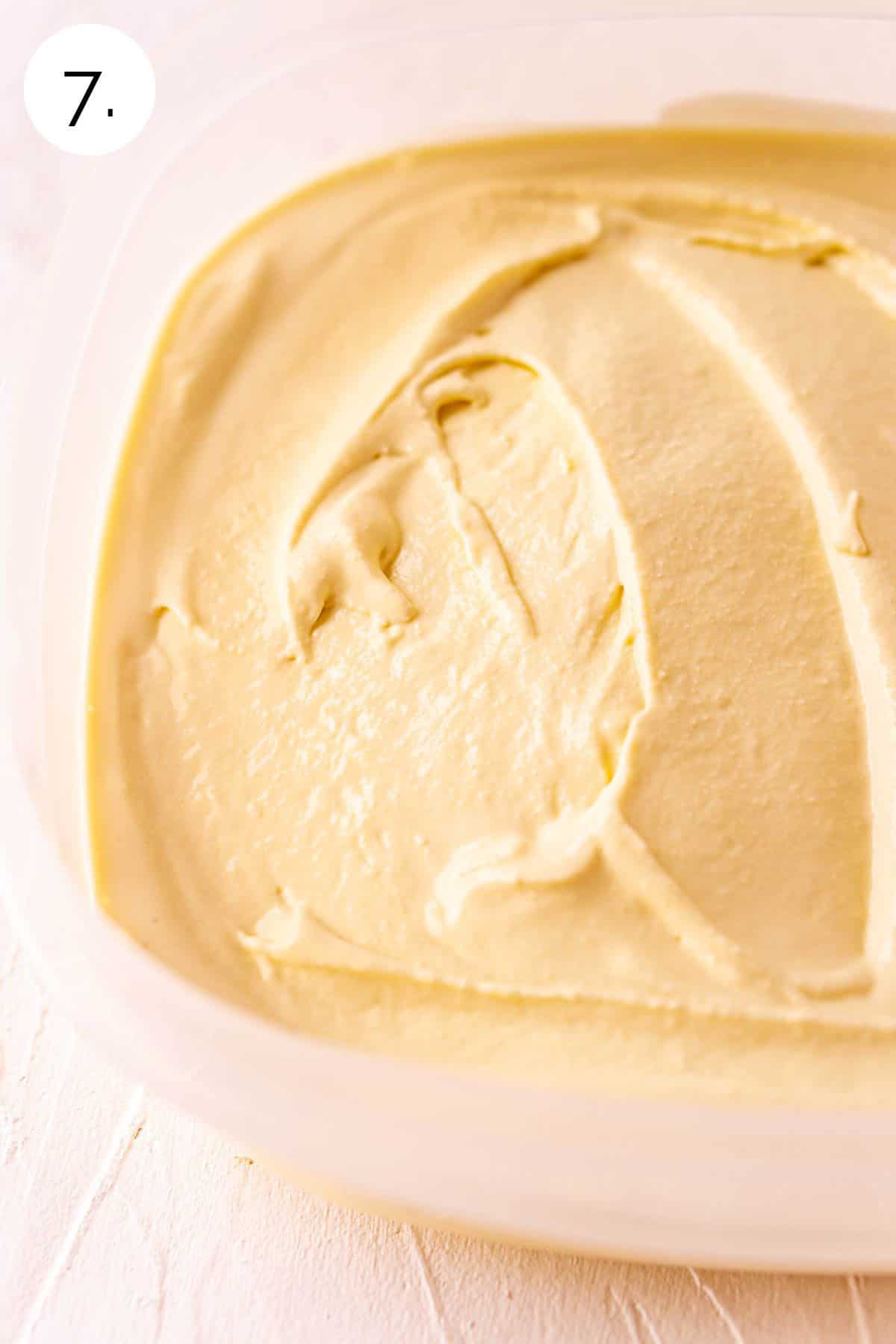 The ice cream spread into a clear plastic container on a white surface before going into the freezer.