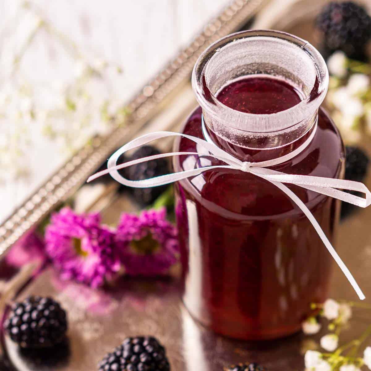 A jar of the blackberry simple syrup on a silver tray.