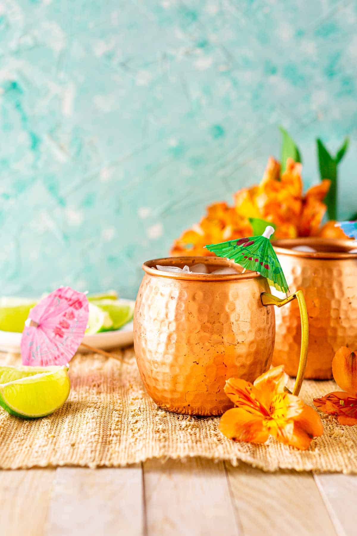 Looking straight on to a Jamaican mule on a straw placemat with tropical orange flowers in the background.