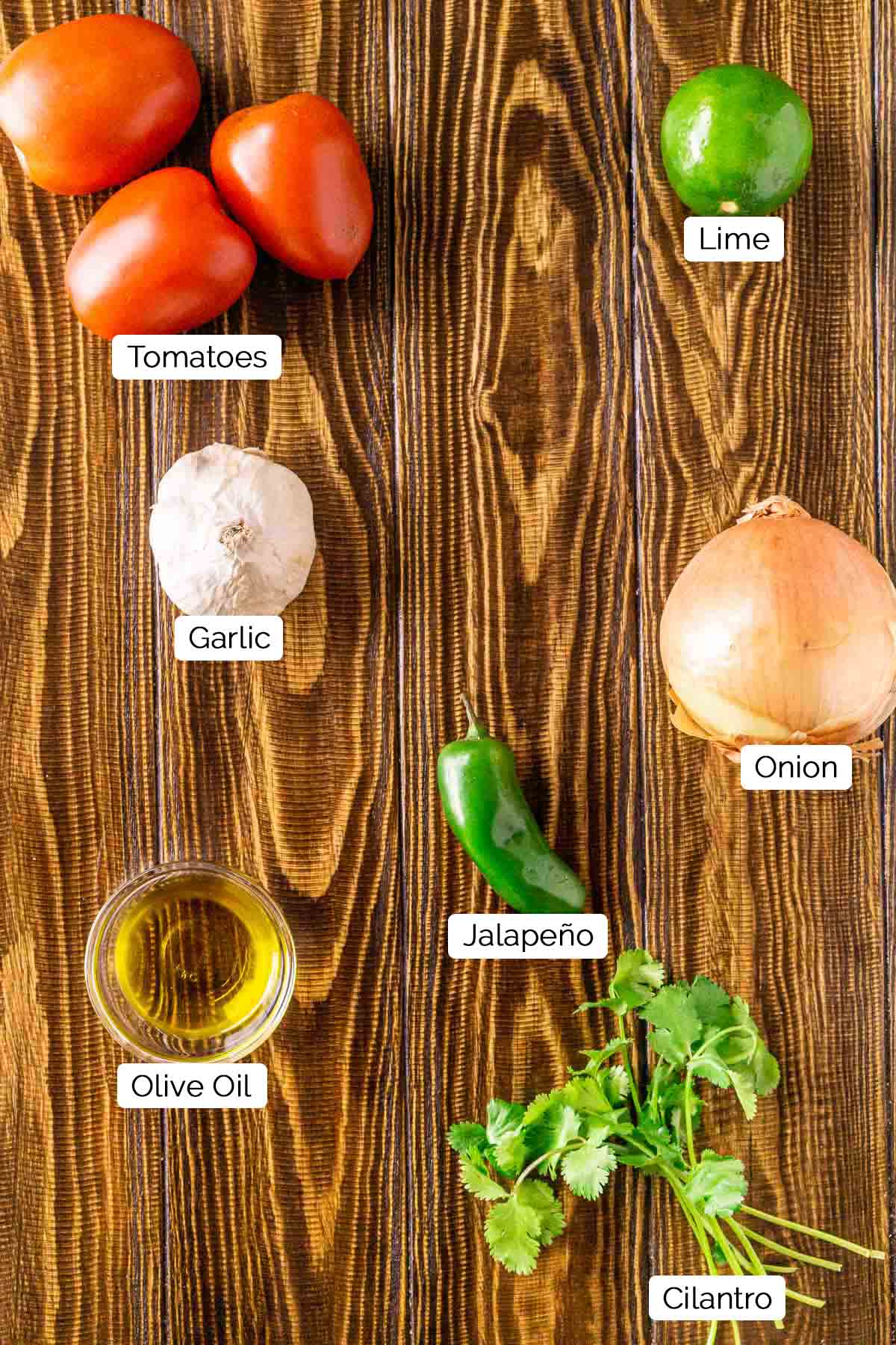 The salsa ingredients on a brown wooden surface with black and white labels by the various items.