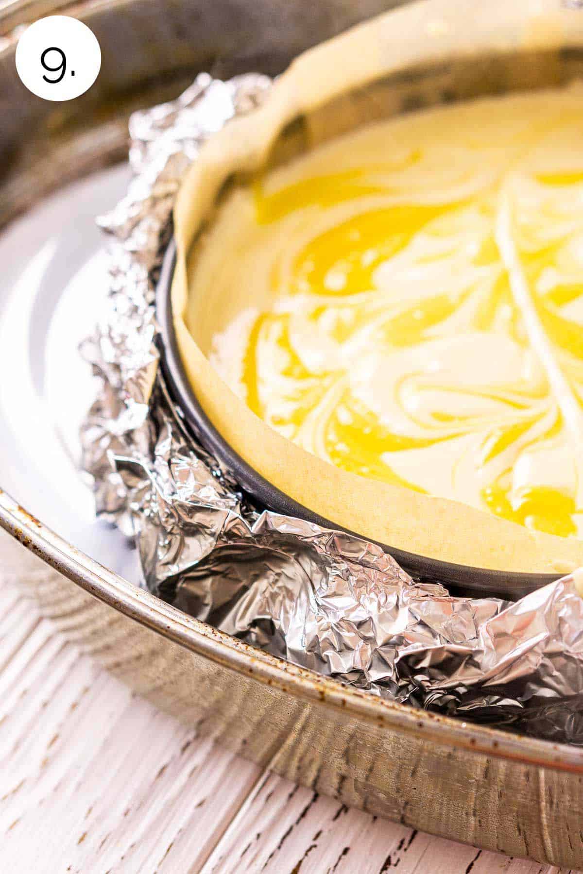 The swirled cheesecake in a large roasting pan with the water bath before baking in the oven.