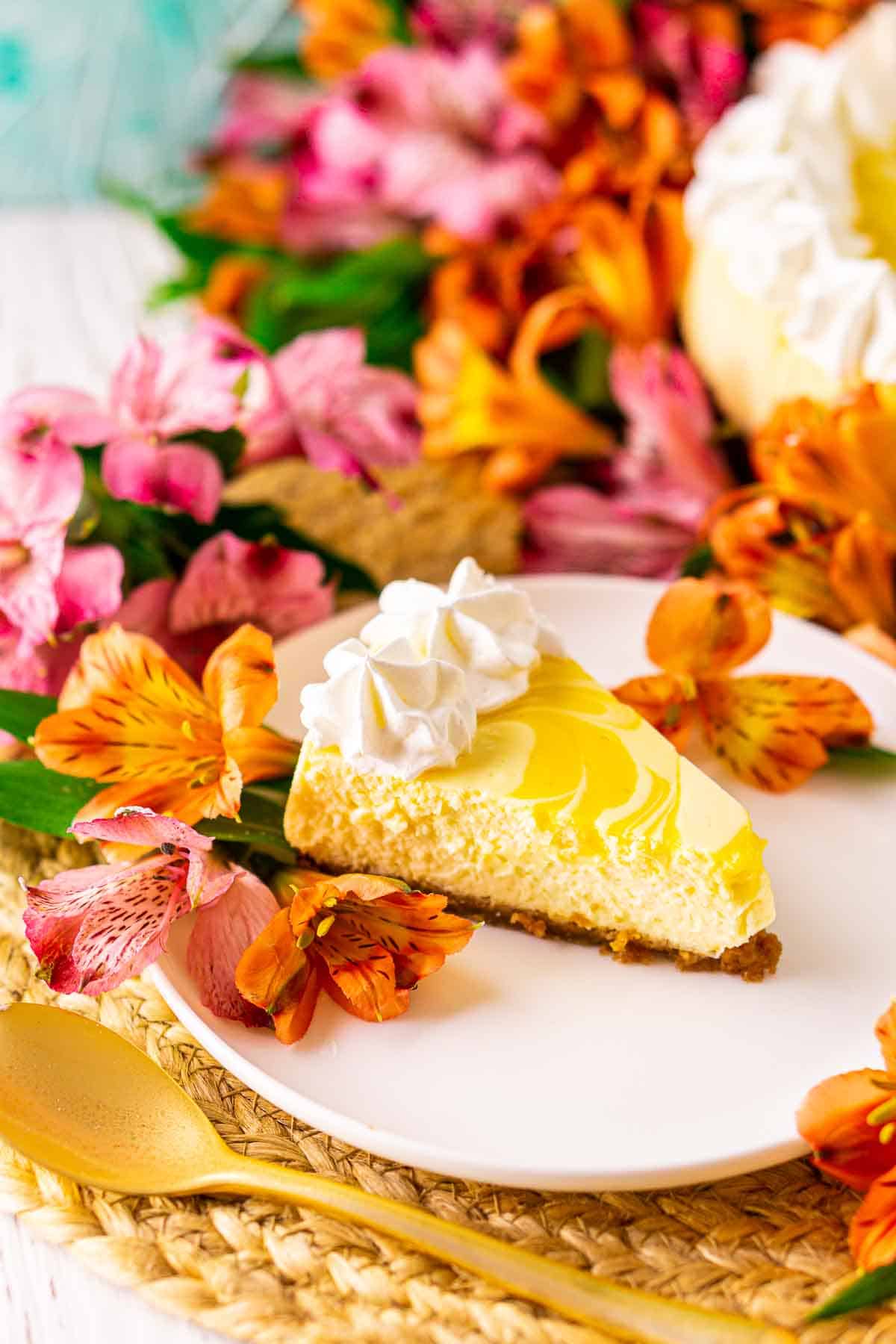 Looking down on a slice of passion fruit cheesecake on a straw placemat with colorful flowers and a blue background.